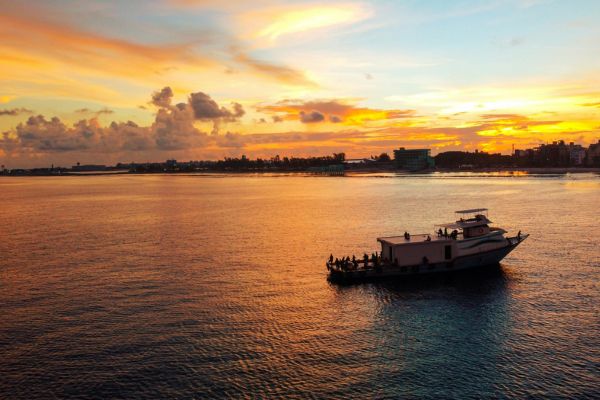 Maldives beach in September with turquoise lagoon and overwater villas under partly cloudy sky